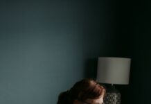 독감 유행 시기에 알아두면 좋은 예방 수칙 woman in white crew neck t-shirt sitting on gray sofa