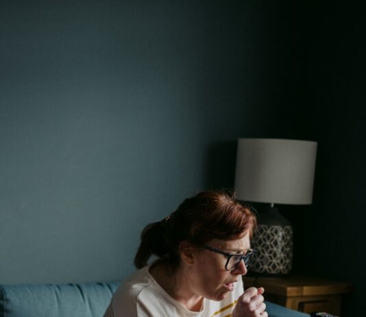 독감 유행 시기에 알아두면 좋은 예방 수칙 woman in white crew neck t-shirt sitting on gray sofa