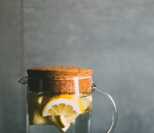 다이어트 성공을 돕는 겨울철 생활 팁 clear glass pitcher filled with sliced lemons on black and white table runner