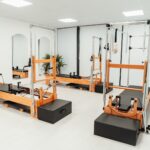 MZ세대와 시니어 모두 사로잡은 필라테스, 올해 건강 트렌드로 급부상 a gym with a row of machines and mirrors