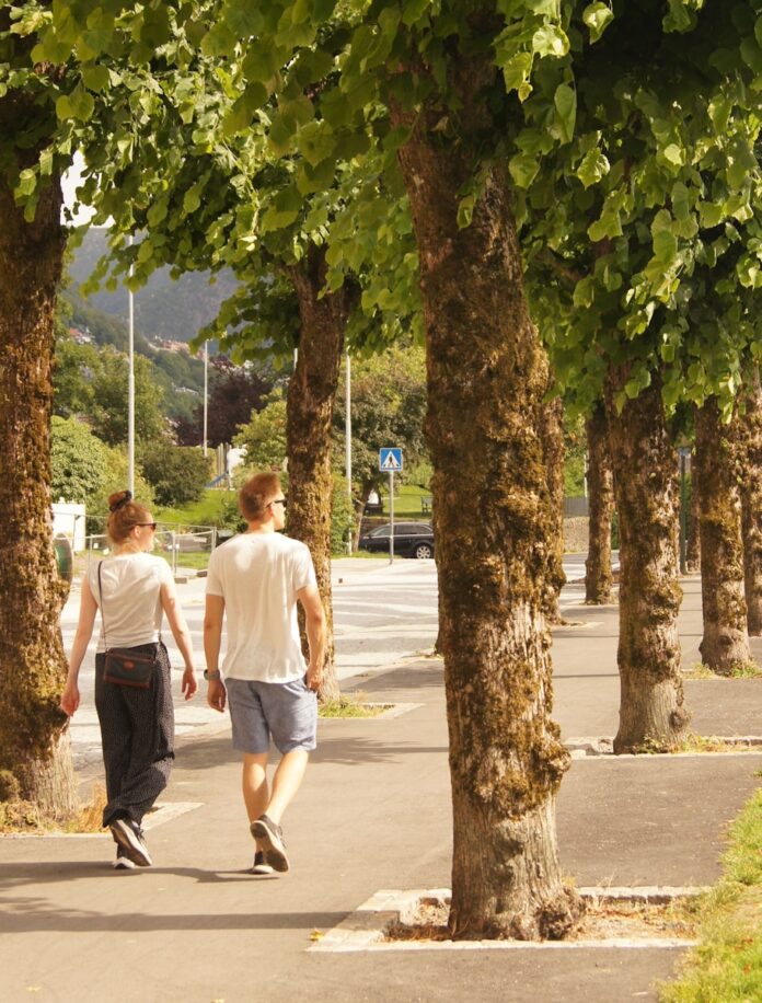 Photo by Alan Bowman man in white t-shirt walking on sidewalk during daytime