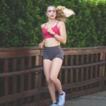 “필라테스, 바쁜 일상 속 균형 찾기의 비밀” Young woman running on a wooden path outdoors path outdoors.