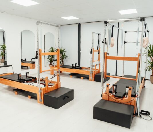 필라테스, 바쁜 일상 속 건강한 움직임 찾는 비결로 인기 a gym with a row of machines and mirrors