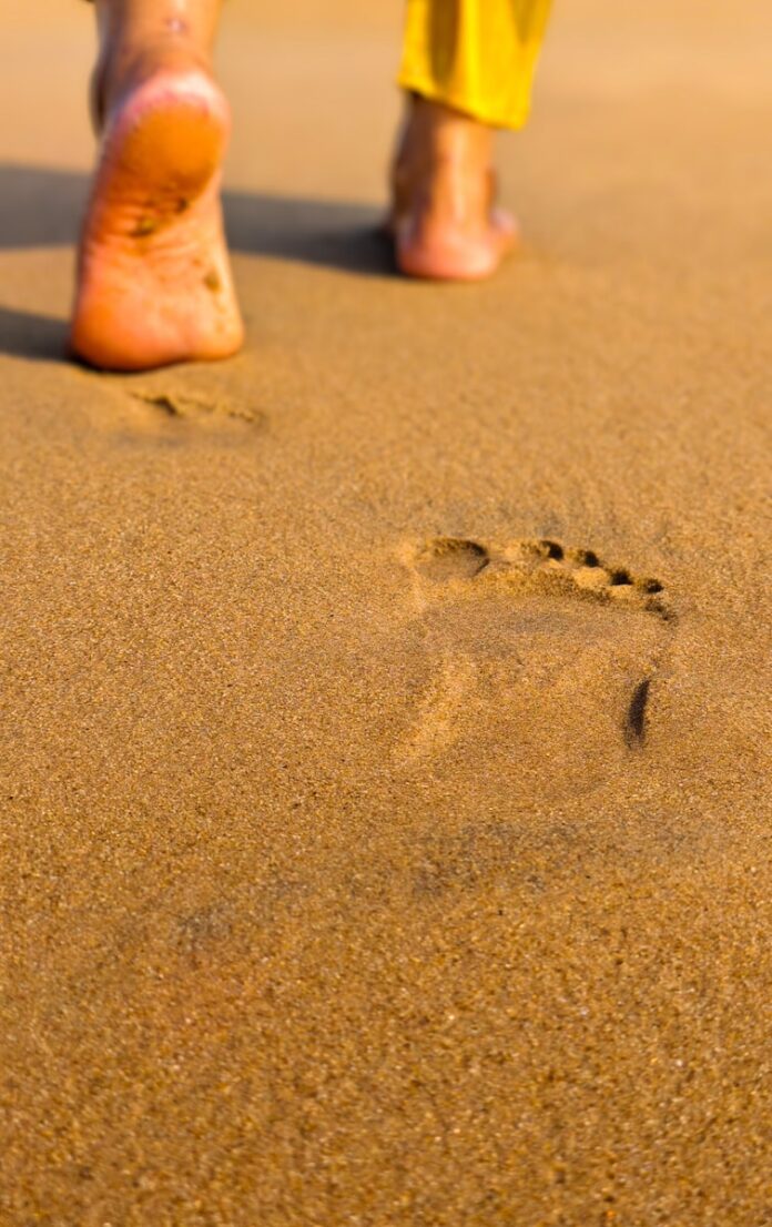 Photo by Debabrata Hazra Footprints on a sandy beach leading away