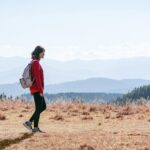똑똑하게 걷기, 나를 가꾸는 가장 쉬운 건강 습관 a man with a backpack walking across a dry grass covered field