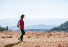 똑똑하게 걷기, 나를 가꾸는 가장 쉬운 건강 습관 a man with a backpack walking across a dry grass covered field