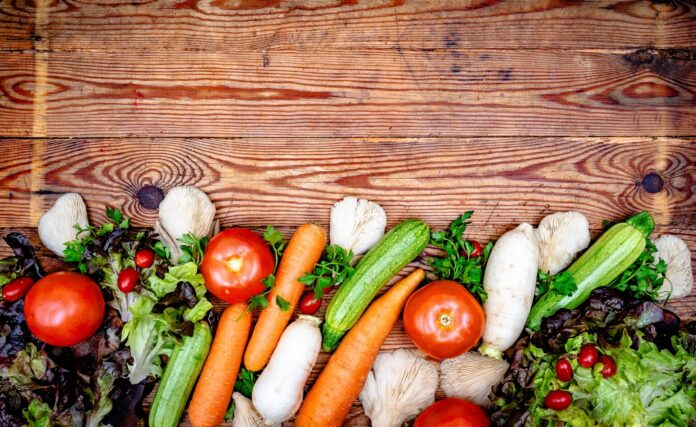 Fresh colorful vegetables arranged on a rustic wooden background.